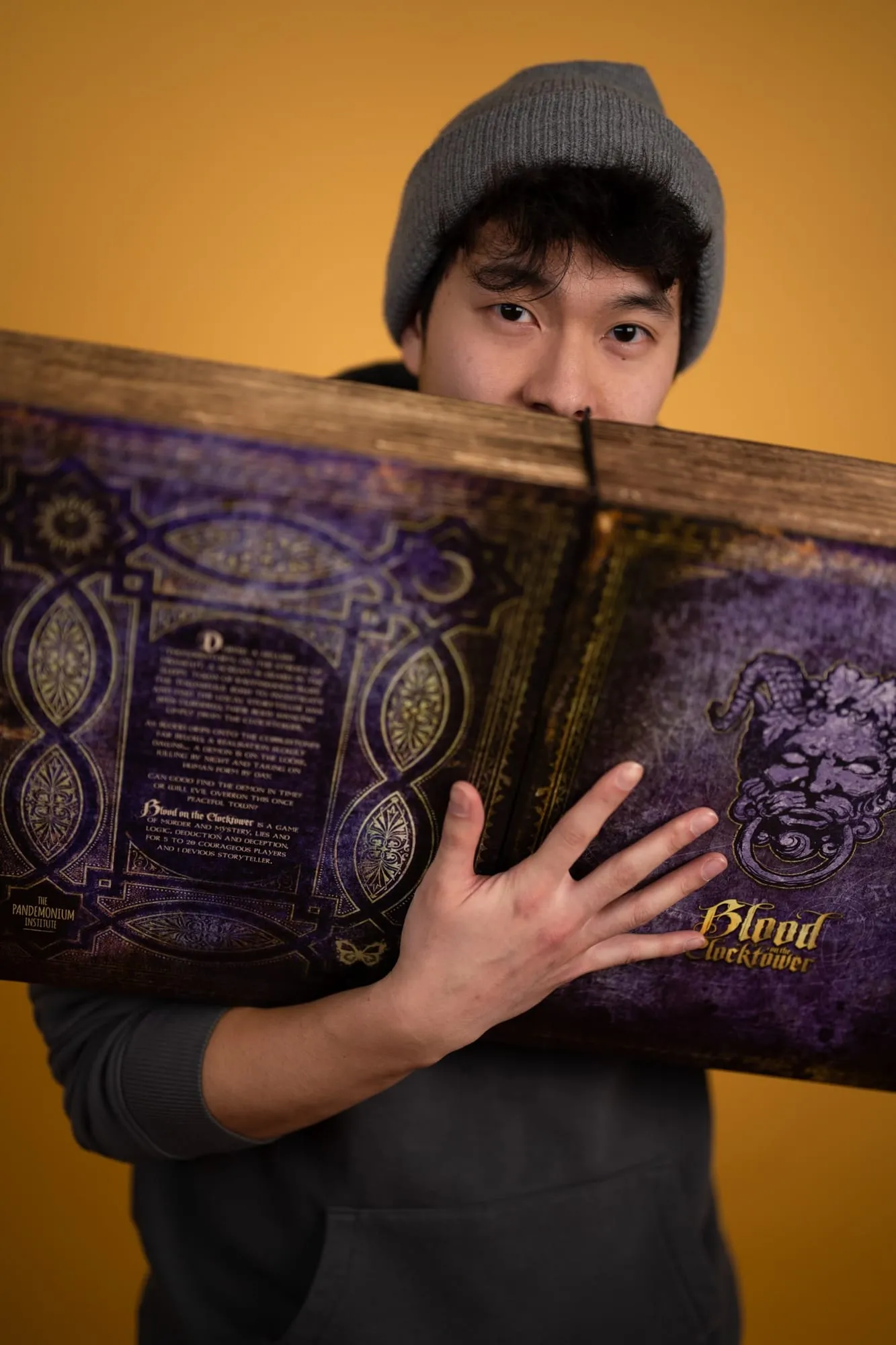 A man peering over the top of a large illustrated menu in a dim restaurant.